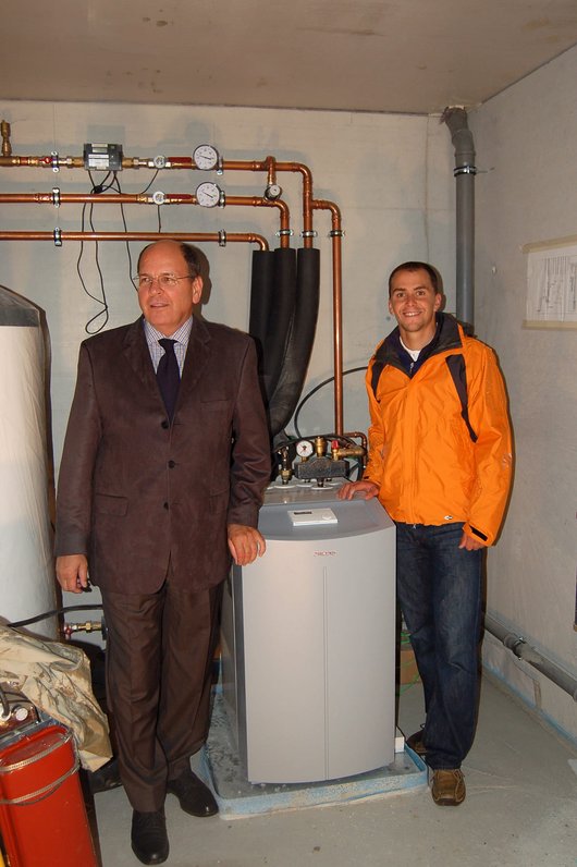 Biathlet Michael Greis (rechts) und Dr. Ulrich Stiebel im Technikraum des Neubaus mit der Wärmepumpenanlage von STIEBEL ELTRON. Foto: Stiebel Eltron 