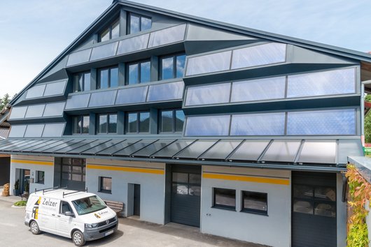 Das Firmengebäude der ortsansässigen Sanitär- und Heizungsfirma Zelzer fungiert als Heizzentrale des Nahwärmenetzes im Gewerbegebiet Bodenmais. An die Außenfassade wurden dabei über eine Fläche von 110m² Solarthermie-Kollektoren eingebaut, welche eine tragende Säule im regenerativen Energiemix des Nahwärmenetzes spielen. (Foto: ratioplan, Dollnstein) Heizzentrale des Nahwärmenetzes im Gewerbegebiet Bodenmais (Foto: ratioplan, Dollnstein)