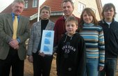Bürgermeister Nebelo (l.) überreicht Familie Breuer Energiespar-Plaketten für ihr 3-Liter-Haus mit Erdwärme und Solarstrom (Foto: Stadt Bocholt)